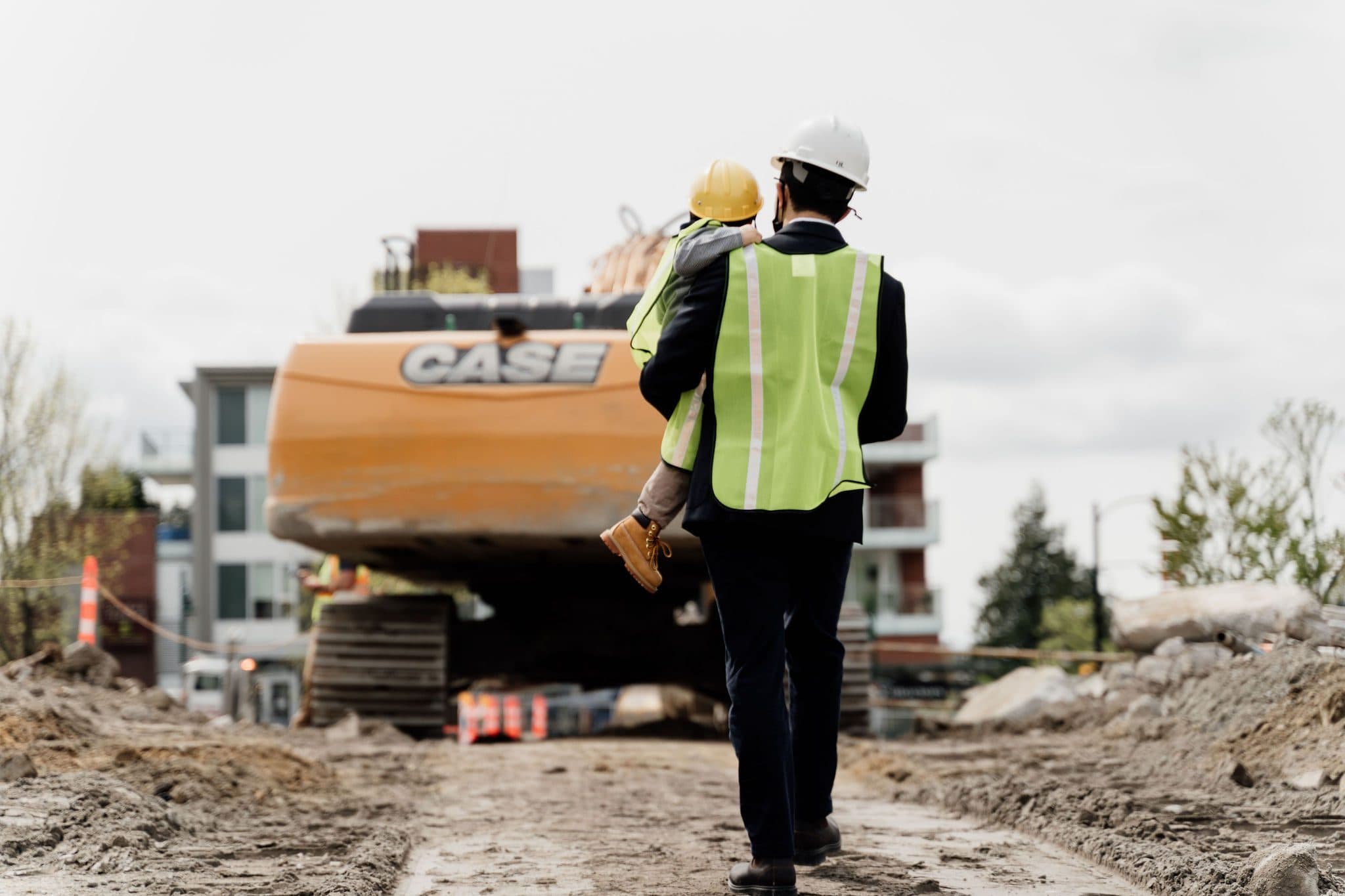 A Qualex-Landmark team member carrying a child across a construction site